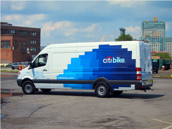 Business van wrapped in colorful vinyl displaying a company logo, contact information, and promotional message.