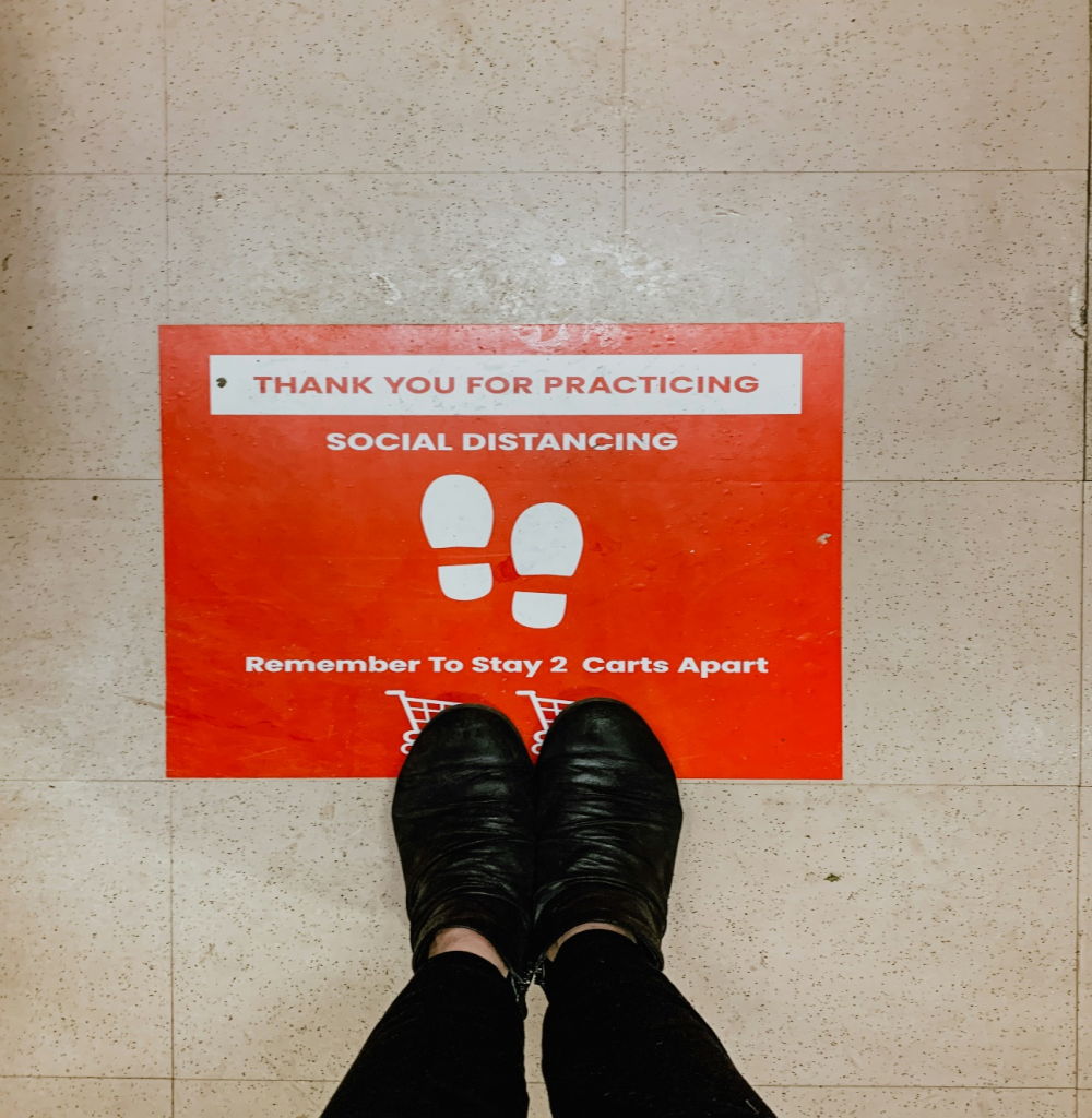Floor decal with text reminding people to practice social distancing.