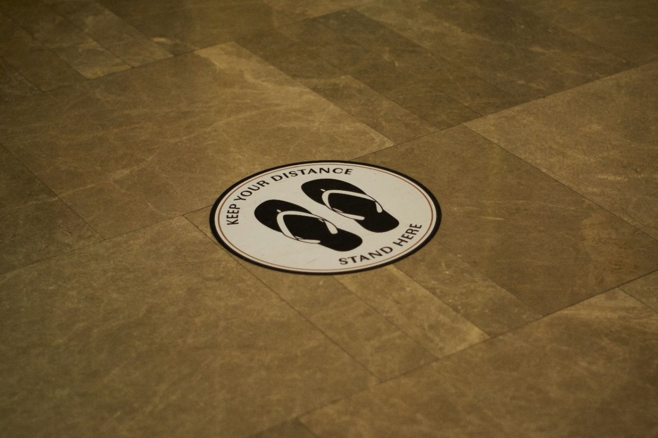 "Stand Here" decal printed on a tile floor