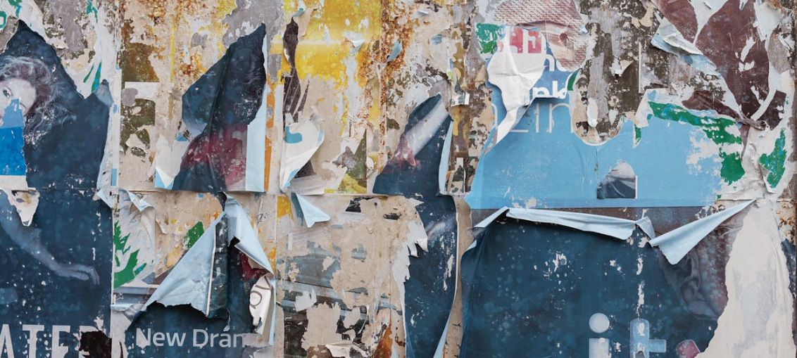 Peeling graphic posters on a notice board and wall, giving an unprofessional and worn-out appearance