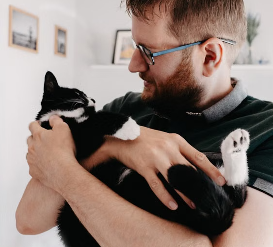 Man holding a tuxedo cat indoors for a custom pet canvas portrait