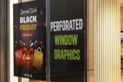 Large printed promotional window graphics applied across a retail storefront